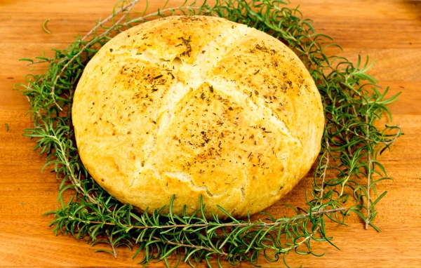 Буханка свежего ароматного хлеба с розмарином на столе