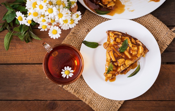 Кружка ромашкового чая на столе с куском пирога