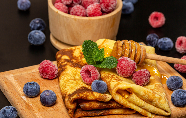 Аппетитные блины с малиной и черникой на столе