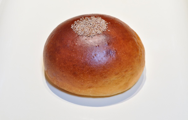 Аппетитная круглая булочка на сером фоне