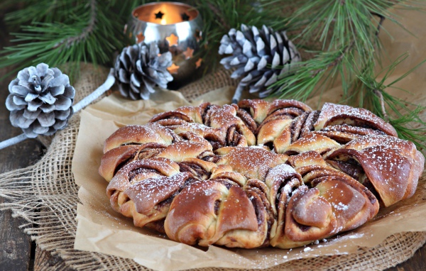 Сдобный венок с вареньем на столе с шишками