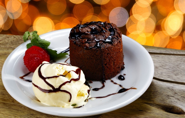Шоколадный десерт с мороженым и клубникой на белой тарелке 