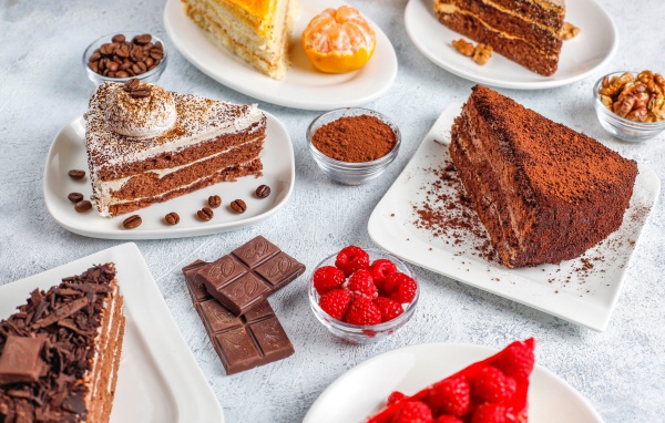 Разные куски торта на столе с малиной и шоколадом 