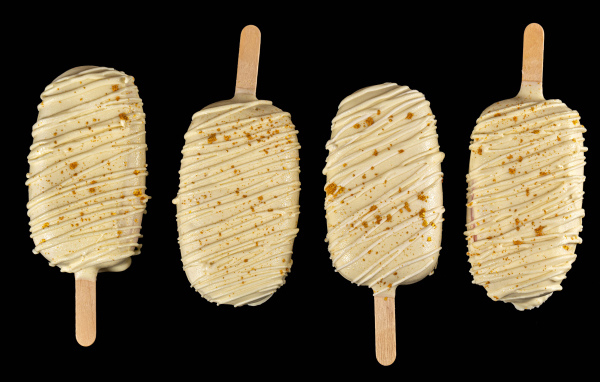 Мороженое на палочке в белом шоколаде на черном фоне