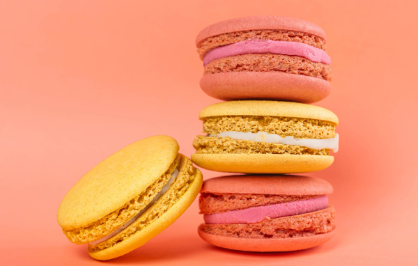 Разноцветный десерт макарон на розовом фоне