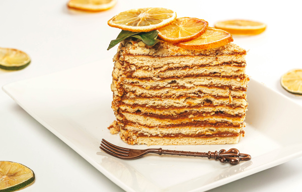Кусок торт с сушеными лимонами на белой тарелке