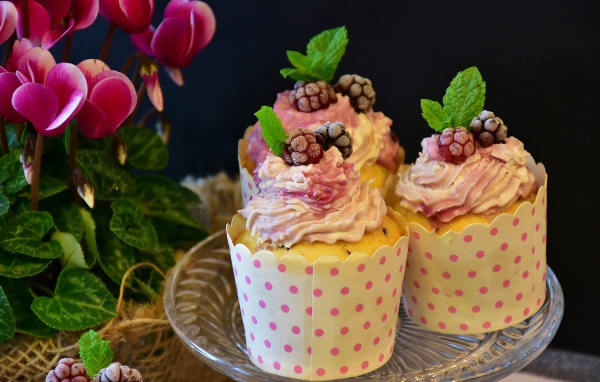 Три кекса с кремом на столе с цветами 