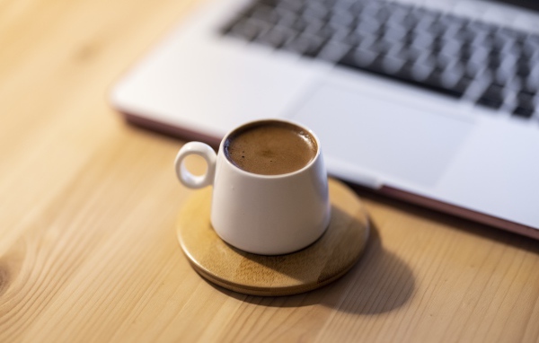 Чашка кофе стоит у ноутбука 