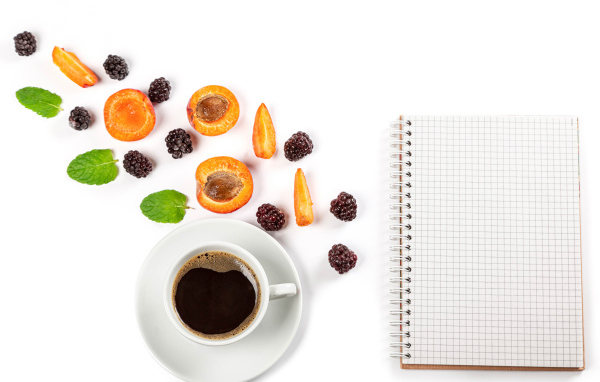 Чашка кофе, тетрадь, черника и абрикос на белом фоне