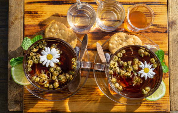 Две чашки чая с ромашкой на столе с медом