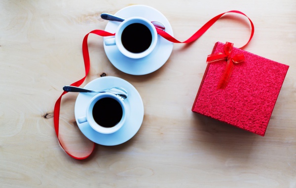 Две чашки кофе на столе с подарком