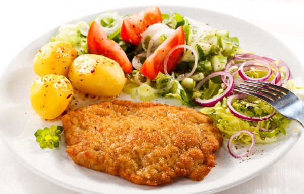 Отбивная с курицы на тарелке с картофелем и овощами 