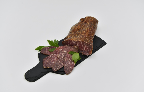 Cured meat on a board on a gray background