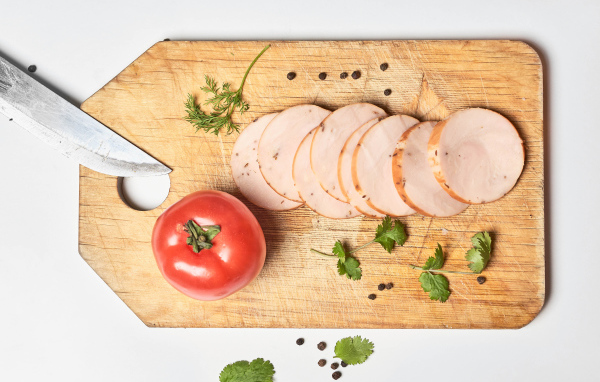 Ветчина на разделочной доске с помидором