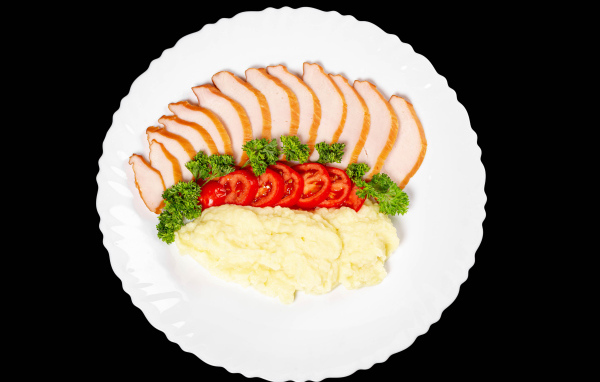 Ветчина на большой белой тарелке с картофелем и помидорами