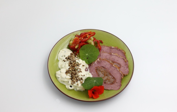Мясо с соусом и овощами на тарелке на сером фоне