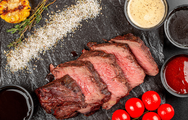 Мясо с помидорами и соусами на доске 