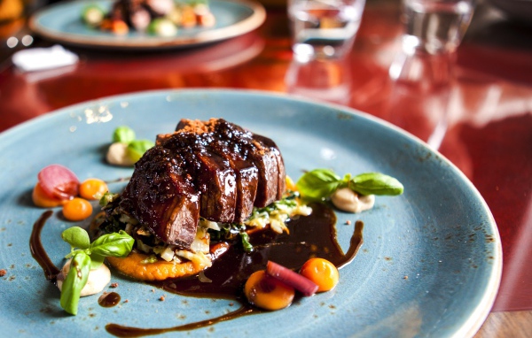 Кусок мяса с соусом на тарелке в ресторане