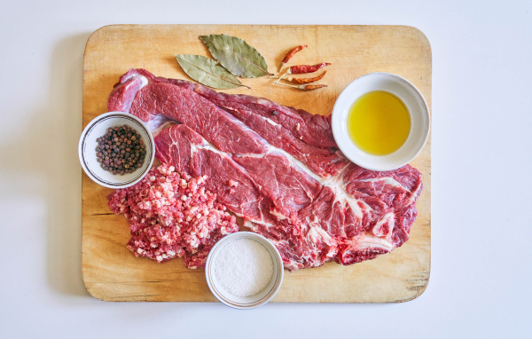 Кусок мяса со специями и оливковым маслом на доске 