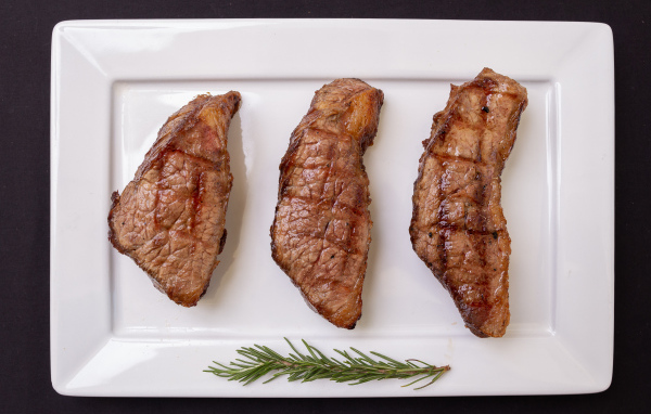 Три куска жареного мяса на большой белой тарелке