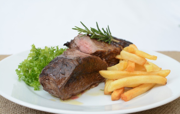 Два куска мяса на тарелке с картофелем фри 