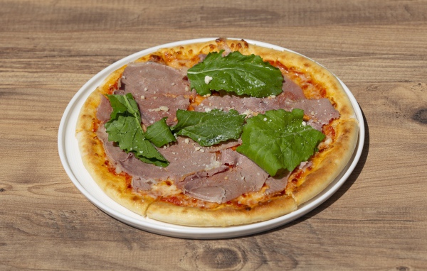 Пицца с кусочками мяса и зеленью на столе