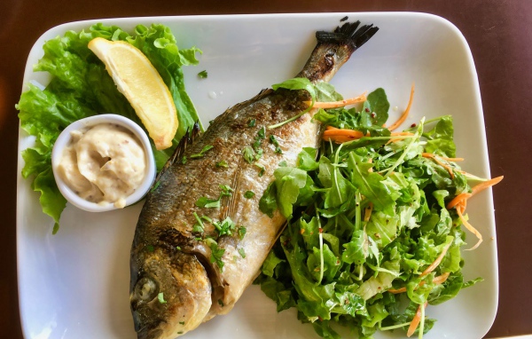 Жареный карась на тарелке с салатом 