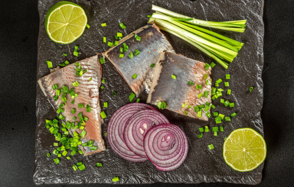 Куски сельди с луком и кусочками лимона