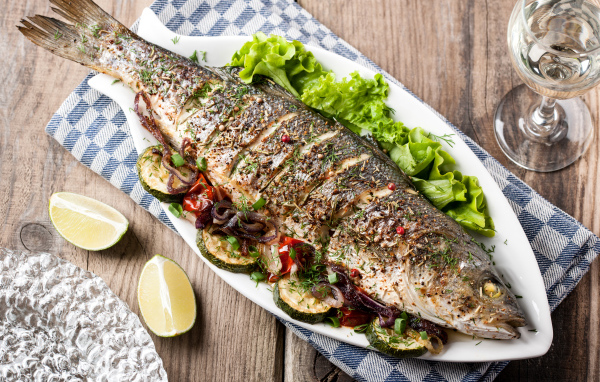 Большая запеченная рыба с кабачками и листьями салата