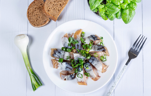 Куски скумбрии на столе с луком, хлебом и базиликом