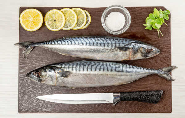Две свежие скумбрии на доске с лимоном 