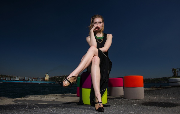 Девушка в черном платье сидит у воды