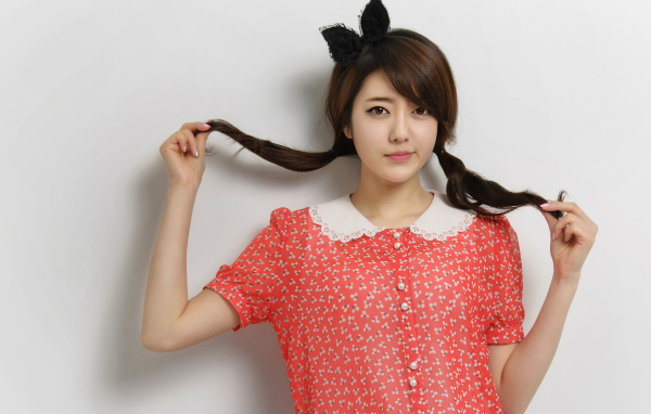 Девушка азиатка в платье стоит у стены 