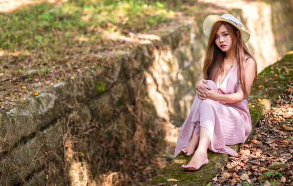 Девушка азиатка в розовом платье сидит на земле