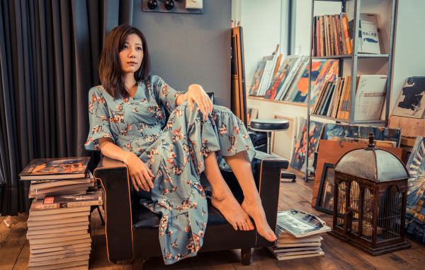 Asian girl sitting in a big chair in a room with books
