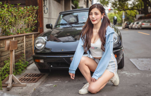 Девушка азиатка сидит возле машины 