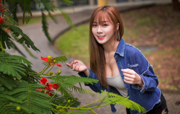 Девушка азиатка стоит у растения с зелеными листьями