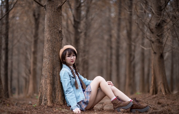 Девушка азиатка школьница сидит под деревом