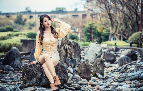 Красивая девушка азиатка сидит на камне