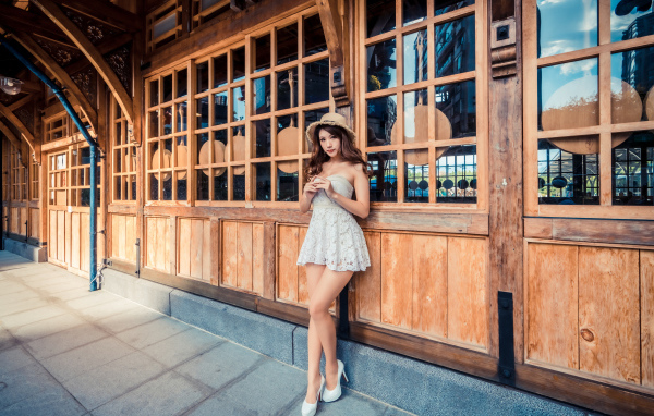 Красивая девушка азиатка стоит у стены с большими окнами