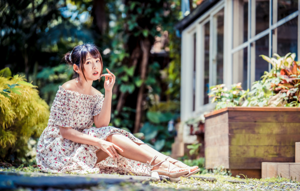 Красивая девушка азиатка в платье сидит на земле