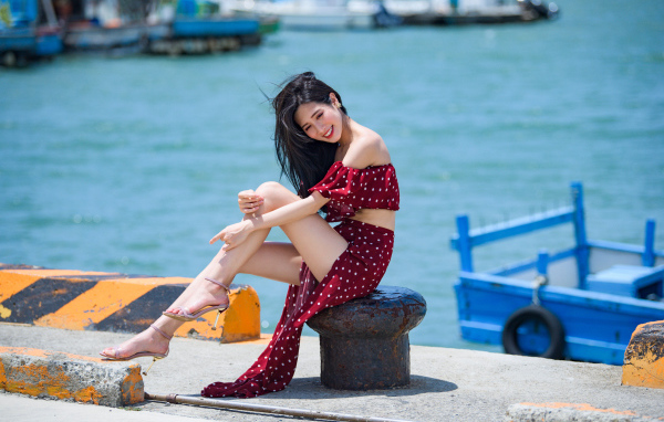Красивая девушка азиатка в платье в горох у моря