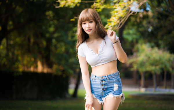 Красивая девушка азиатка в синих джинсах в парке