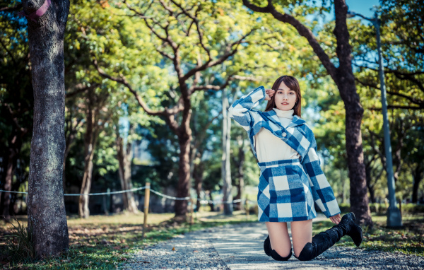 Красивая девушка азиатка стоит на коленях в парке