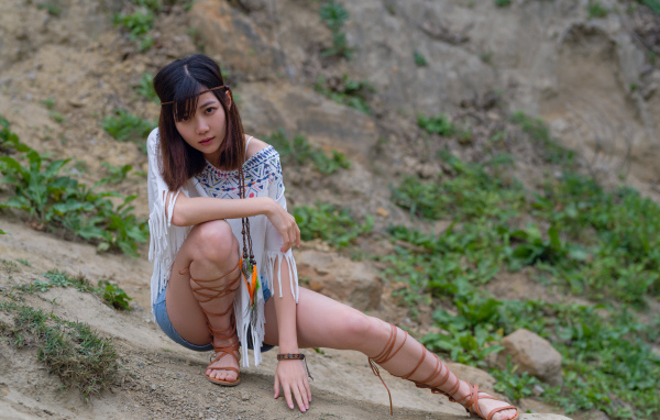 Красивая девушка азиатка сидит на земле  в туфлях