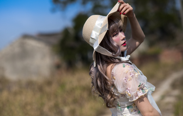 Красивая азиатка в шляпе в лучах солнца