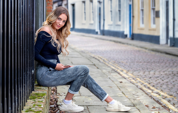 Красивая девушка блондинка сидит у забора