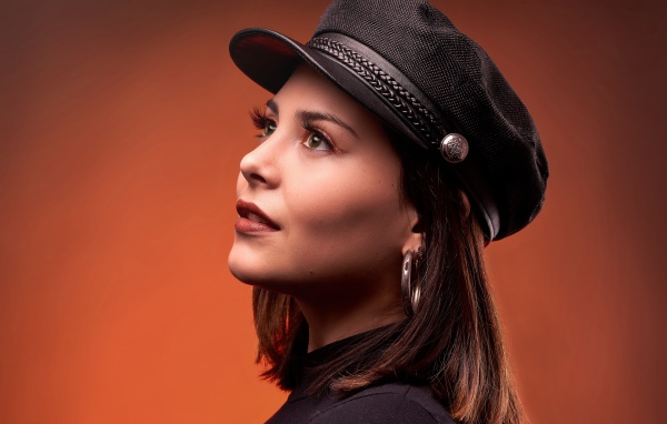 Красивая девушка в кепке на коричневом фоне