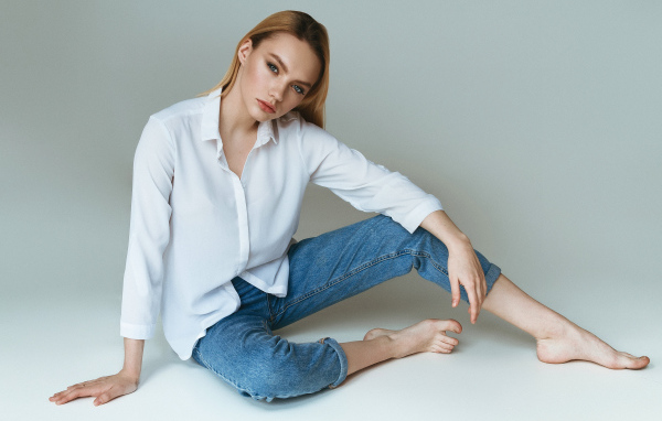 Красивая девушка в белой рубашке на сером фоне