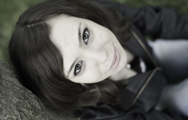 Красивая девушка смотрит вверх сидя под деревом  